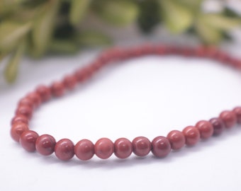 May include: A red gemstone bracelet with round beads. The bracelet is made of natural stone and has a simple design.
