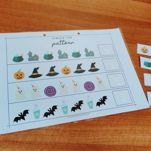 Puede incluir: Una hoja de trabajo imprimible con temática de Halloween con el texto "Finish the pattern". La hoja de trabajo tiene cuatro filas de imágenes, cada una con una imagen que falta. Las imágenes que faltan se muestran en tarjetas separadas. Las imágenes incluyen un caldero, una casa, una calabaza, un sombrero de bruja, un fantasma, un remolino, una botella y un murciélago.