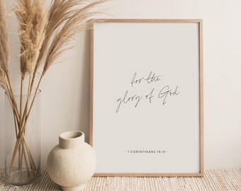 May include: A framed print with the text "for the glory of God - 1 Corinthians 10:31 -" in a minimalist style. The print is displayed on a table with dried pampas grass in a vase.