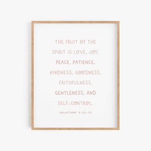 May include: A framed print with a white background and pink text. The text reads "The fruit of the spirit is love, joy, peace, patience, kindness, goodness, faithfulness, gentleness, and self-control. Galatians 5:22-23".