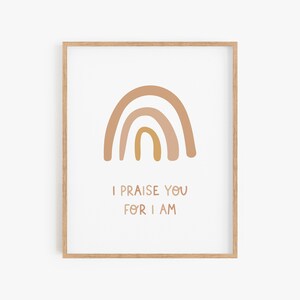 May include: A framed print with a rainbow in shades of brown and yellow. The text "I praise you for I am" is below the rainbow.