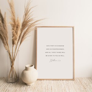 May include: A framed print with a white background and black text. The text reads "Seek first his kingdom and his righteousness, and all these things will be given to you as well. Matthew 6:33".