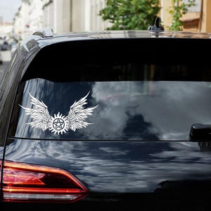 May include: A black car with a white angel wings and pentagram sticker on the back window.