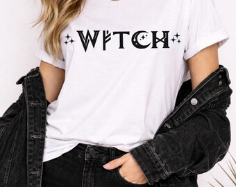 May include: White t-shirt with the word "WITCH" in black, featuring star and crescent moon accents. The shirt is paired with black jeans and a black denim jacket. A gold necklace is visible.