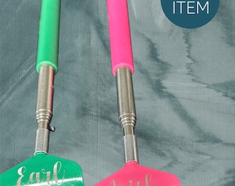May include: Two personalized back scratchers with extendable handles. One is green with the name "Earl" and the other is pink with the name "Ariel".