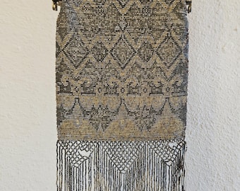 Peut inclure: Un sac à main vintage en perles avec une bandoulière en chaîne argentée et un bas en frange. Le sac est fait de petites perles argentées tissées en un motif géométrique.