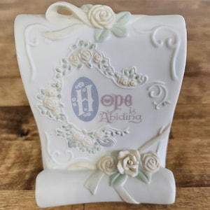 Puede incluir: Rollo de porcelana blanca con un diseño floral y el texto "Hope is Abiding".