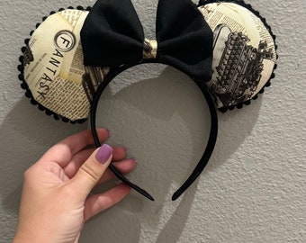 May include: Black and white patterned mouse ears with a black bow. The pattern features the word "Fantasy" and a vintage typewriter.