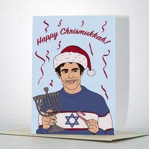 May include: A greeting card featuring a cartoon illustration of a person wearing a Santa hat and a sweater with a Star of David and a candy cane. The text on the card reads "Happy Chrismukkah!"