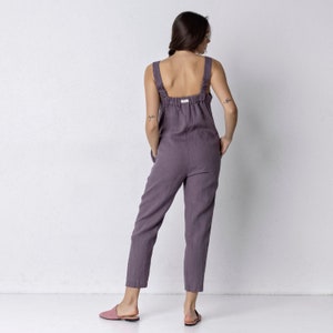 May include: A purple linen jumpsuit with adjustable straps and pockets. The jumpsuit has a relaxed fit and is cropped at the ankle.