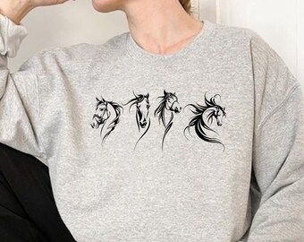 May include: A gray sweatshirt with a black graphic of five horse heads in a row.