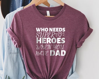 May include: Burgundy t-shirt with a silver graphic that reads "Who needs super heroes when you have dad" with a heart symbol.
