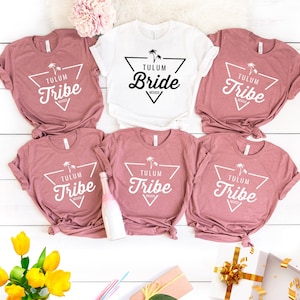 May include: Six pink and white t-shirts with a triangle design and the text "Tulum Tribe" or "Tulum Bride".
