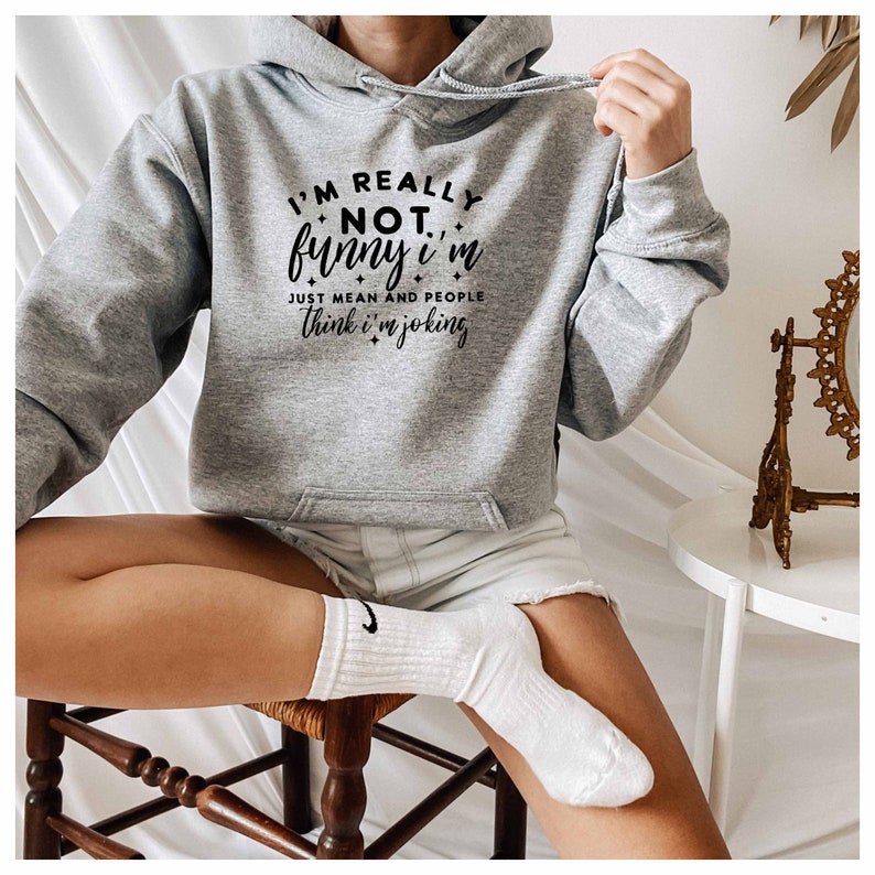 May include: A gray hooded sweatshirt with the text "I'm really not funny I'm just mean and people think I'm joking" printed on the front.