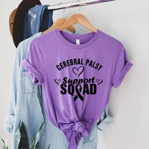 May include: Purple t-shirt with the text "Cerebral Palsy Support Squad" in black lettering with a black ribbon and hearts.