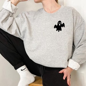 May include: A gray sweatshirt with a black ghost graphic on the left chest. The ghost has a surprised expression with its mouth open.