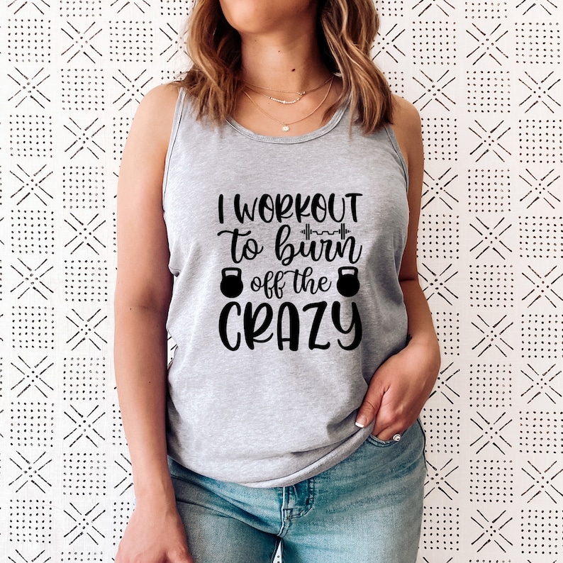 May include: Grey tank top with the text "I workout to burn off the crazy" in black lettering. The text includes a dumbbell graphic and two kettlebell graphics.