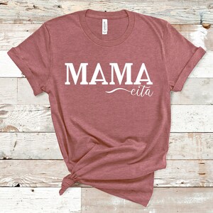 May include: A mauve t-shirt with the text "MAMA eita" printed in white.