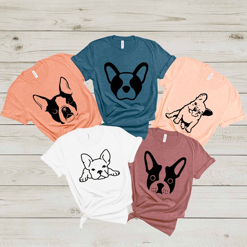May include: Five t-shirts with different French Bulldog designs. The shirts are in various colors, including peach, teal, white, and maroon.