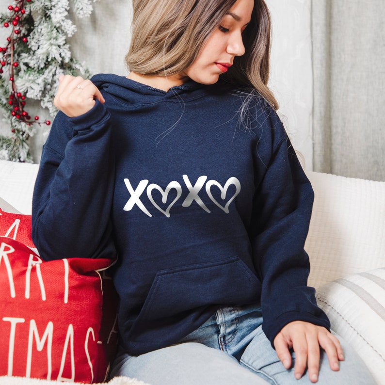 May include: A navy blue hoodie with a silver graphic of the letters "XOXO" with hearts in between.