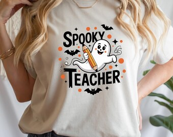 May include: A light beige t-shirt with the words "Spooky Teacher" in black, and a cartoon ghost holding a pencil. Orange dots and bat graphics surround the text, creating a Halloween theme.