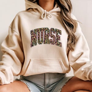 Sudadera con capucha de enfermera con estampado de leopardo, colorida y letras de animales, ideal como regalo para profesionales de la salud seguros.