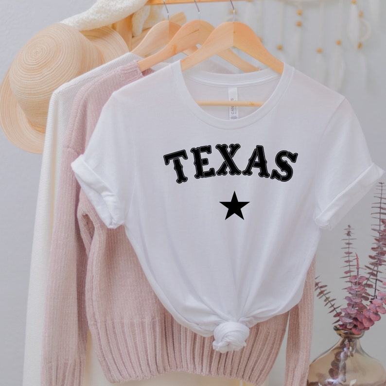 May include: White t-shirt with black text that says "TEXAS" and a black star.