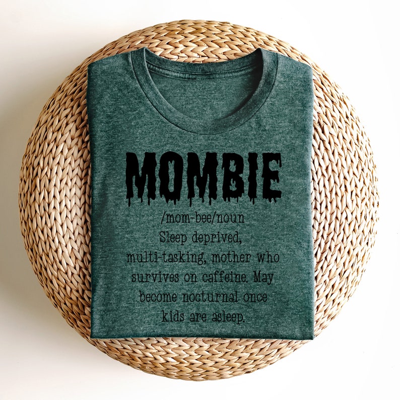 May include: A dark green t-shirt with a black graphic that says "MOMBIE /mom-bee/noun Sleep deprived, multi-tasking, mother who survives on caffeine. May become nocturnal once kids are asleep."