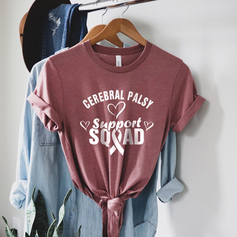 May include: A maroon t-shirt with the text "Cerebral Palsy Support Squad" in white with a white ribbon and hearts.