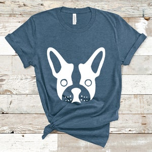 May include: A blue t-shirt with a white silhouette of a French bulldog's face.