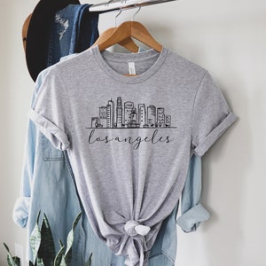 Peut inclure: Un t-shirt gris avec un graphique noir et blanc de l'horizon de Los Angeles et le texte "los angeles" imprim&eacute; sur le devant.