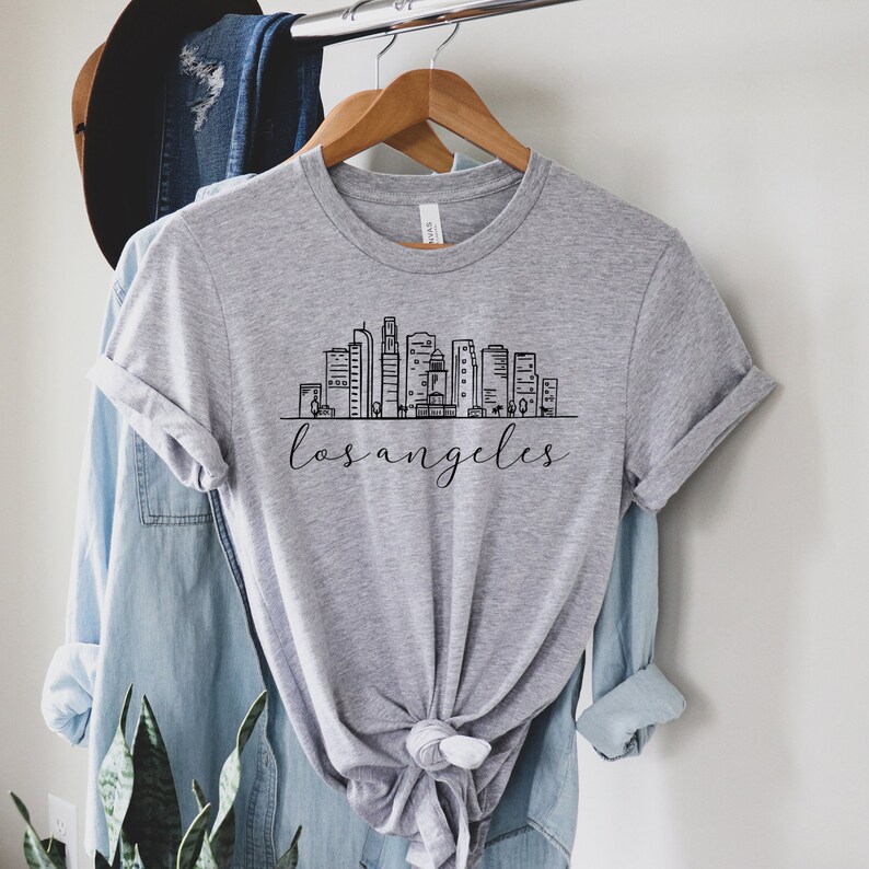 Peut inclure: Un t-shirt gris avec un graphique noir et blanc de l'horizon de Los Angeles et le texte "los angeles" imprim&eacute; sur le devant.