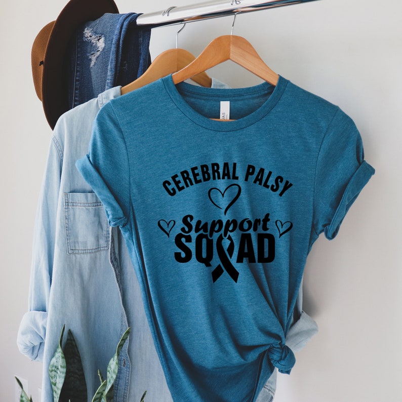 May include: Teal blue t-shirt with black text that reads "Cerebral Palsy Support Squad" with a black ribbon and hearts.