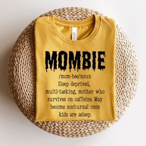 May include: A yellow t-shirt with a black graphic that says "MOMBIE /mom-bee/noun Sleep deprived, multi-tasking, mother who survives on caffeine. May become nocturnal once kids are asleep."