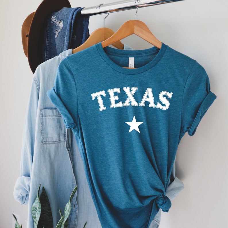 May include: A teal blue t-shirt with a white graphic that says "TEXAS" with a white star underneath.
