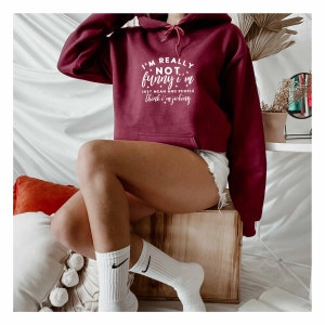 May include: A maroon hoodie with a white graphic that says "I'm really not funny, I'm just mean and people think I'm joking".