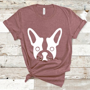 May include: A mauve t-shirt with a white silhouette of a French bulldog's face.