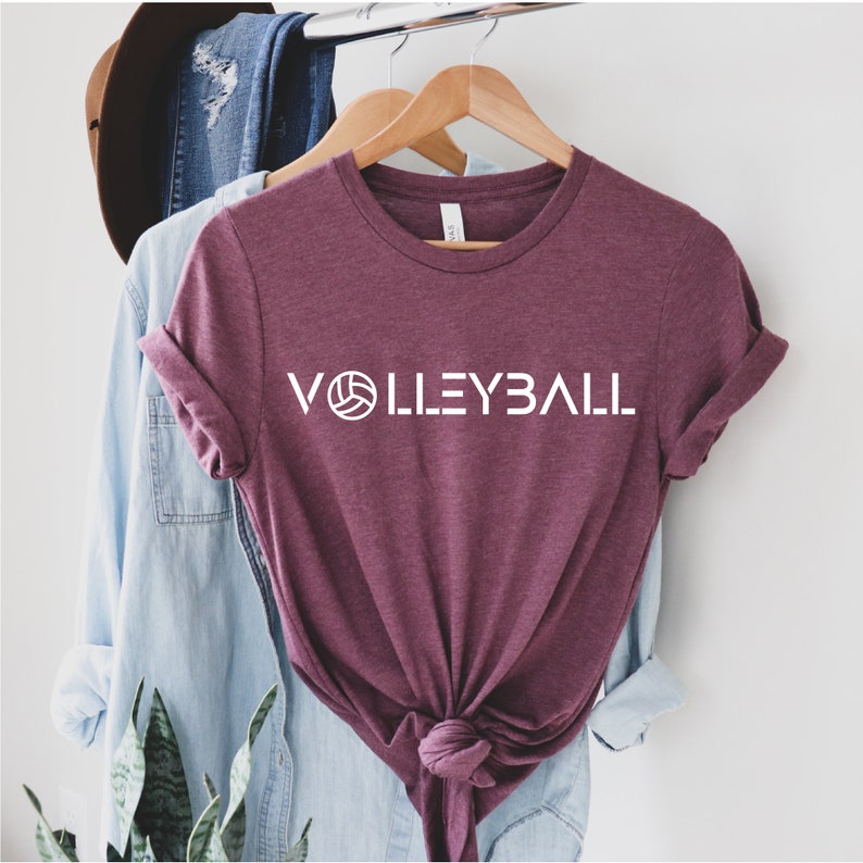May include: A maroon t-shirt with a white volleyball graphic and the word "VOLLEYBALL" printed in white.