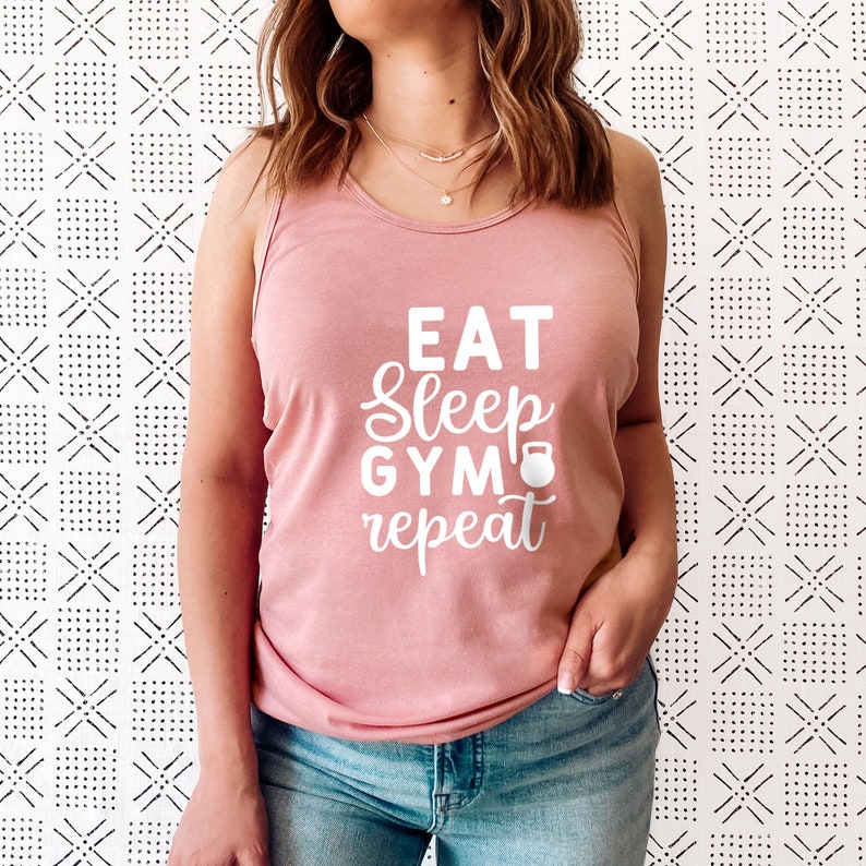 May include: A pink tank top with the text "Eat Sleep Gym Repeat" in white lettering. A small white dumbbell icon is next to the word "Gym".