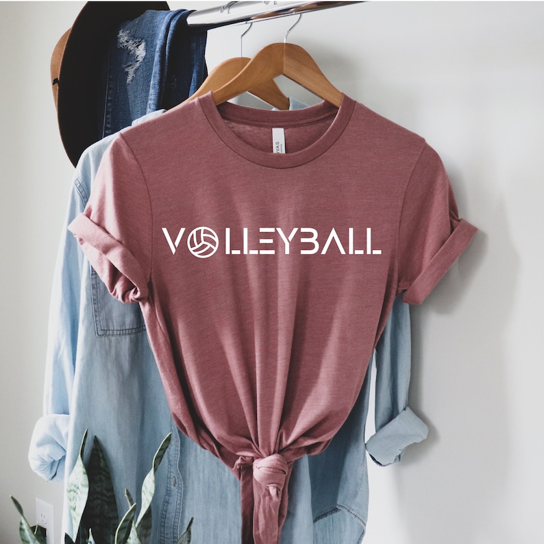 May include: A mauve t-shirt with the word "VOLLEYBALL" printed in white with a volleyball graphic.