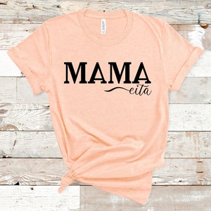 May include: A peach-colored t-shirt with the text "MAMA eita" printed in black.