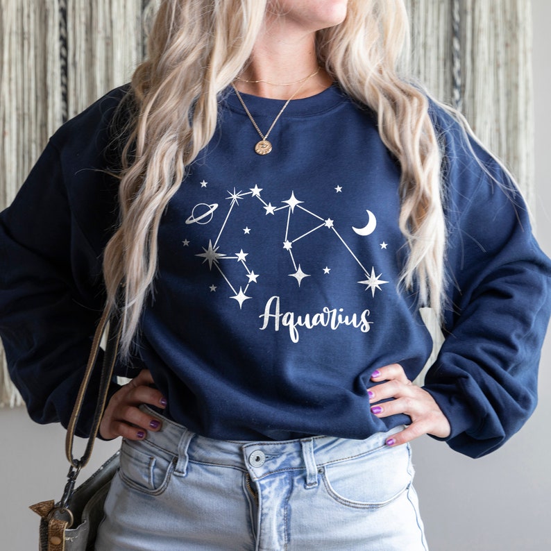 May include: A navy blue sweatshirt with a white constellation design and the word "Aquarius" printed on the front.