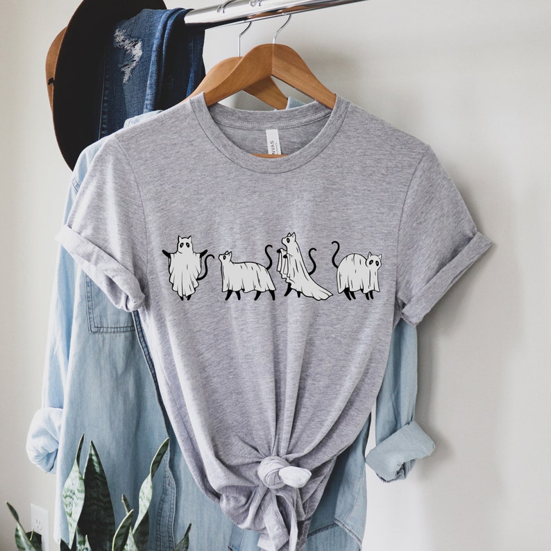 May include: Gray t-shirt with a graphic of five cats dressed as ghosts. The cats are in a line, facing forward, and each has a different pose. The graphic is in black and white.