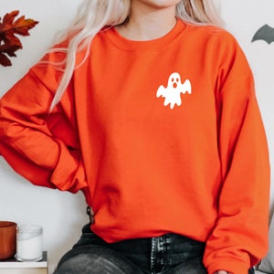 May include: Orange sweatshirt with a white ghost graphic on the front.