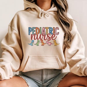 Colorful Pediatric Nurse Dino Hoodie, Cute NICU Medical Gift for Healthcare Professionals Working with Kids