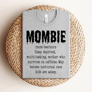 May include: A gray t-shirt with a black graphic that says "MOMBIE" and defines it as a "sleep deprived, multi-tasking mother who survives on caffeine. May become nocturnal once kids are asleep."