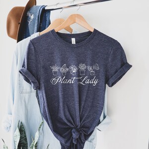 K&ouml;nnte beinhalten: Ein marineblaues T-Shirt mit einer wei&szlig;en Grafik von Topfpflanzen und dem Text "Plant Lady".