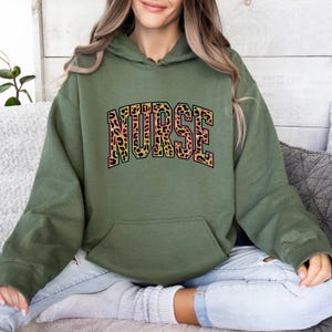 Sudadera con capucha de enfermera con estampado de leopardo, colorida y letras de animales, ideal como regalo para profesionales de la salud seguros.