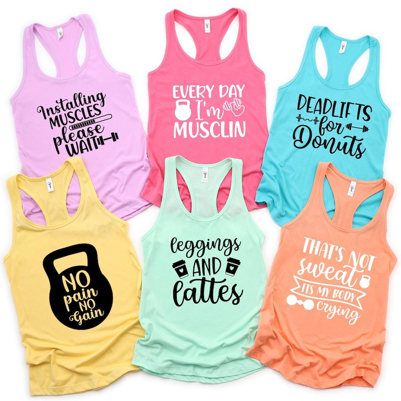 May include: Six tank tops with different fitness-themed slogans printed on them. The tank tops are in various colours, including pink, turquoise, yellow, and orange. The slogans include "Installing Muscles Please Wait", "Every Day I'm Musclin", "Deadlifts for Donuts", "No Pain No Gain", "Leggings and Lattes", and "That's Not Sweat It's My Body Crying".