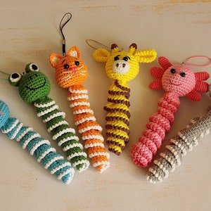 May include: Six crocheted animal toys with long, spiral bodies. The toys are a green frog, an orange cat, a yellow giraffe, a pink axolotl, a gray elephant, and a blue bunny.